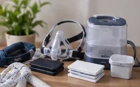 CPAP mask, hose, humidifier chamber and filters laid out on a table